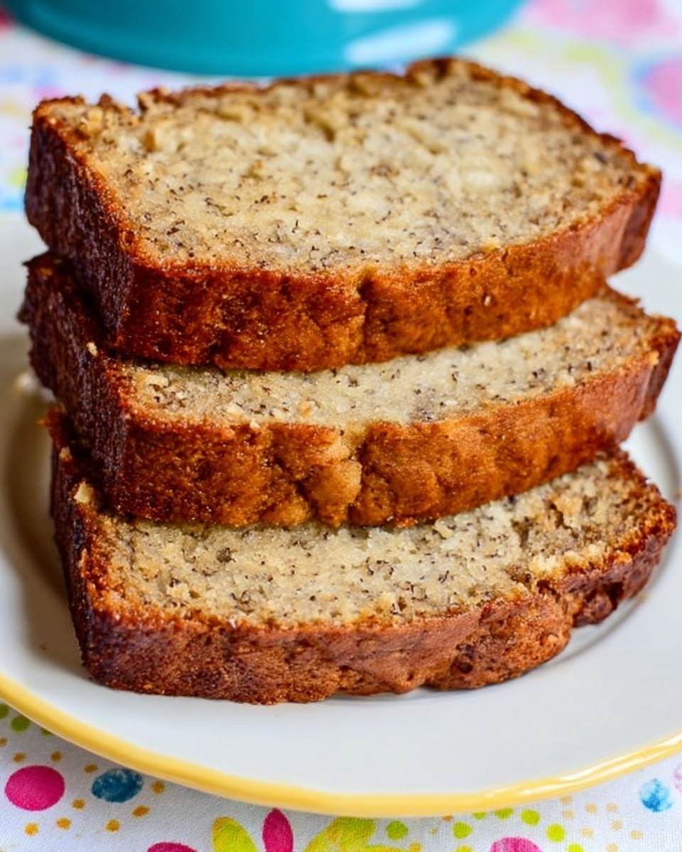 Three thick slices of banana bread are stacked one on top of the other on a white plate that has a thin yellow rim. The bread has a golden-brown crust with a slightly rough texture, and the inside is light brown with visible small bits of banana. The plate sits on a colorful surface with polka dots and floral patterns, but this detail is not dominant. photo taken with an iphone --ar 4:5 --v 7