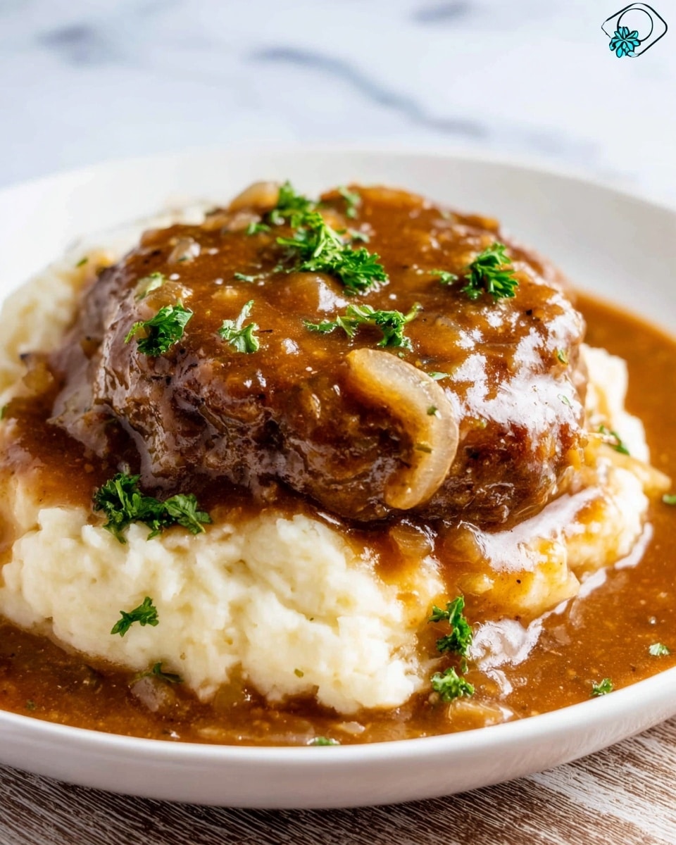 A white plate holds a dish with two main layers: the bottom layer is creamy, white mashed potatoes with a soft, slightly textured surface and a light sheen. The top layer is a thick, brown hamburger patty covered in rich brown gravy with small chunks of onion visible throughout. The gravy also spreads around the base of the mashed potatoes. Fresh green parsley pieces are sprinkled on top of the patty, adding a fresh contrast in color. The plate rests on a white marbled surface. photo taken with an iphone --ar 4:5 --v 7