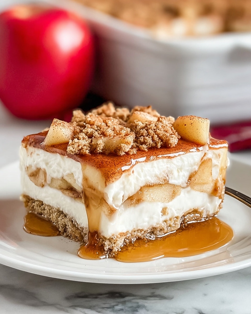 A square slice of dessert on a white plate shows three clear layers: the bottom layer is a crumbly light brown crust, the middle layer is thick and creamy white, and the top layer has small, soft apple pieces mixed with a light brown cinnamon powder sprinkled over them. Syrup is glossy and golden, dripping slightly down the sides and pooling a bit on the plate. In the background, there is a blurred baking dish and a red apple on a white marbled texture. photo taken with an iphone --ar 4:5 --v 7