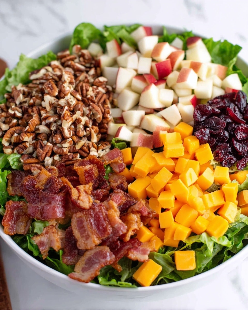 A white bowl filled with a fresh salad shows five distinct layers placed side by side on a bed of green leafy lettuce. Starting from the top left, there is a mound of brown chopped pecans with a rough texture. Next to the pecans, white and red pieces of diced pear with smooth skin and soft inner flesh are placed. Below the pear, crispy orange-brown bacon pieces with a slightly shiny surface are arranged. To the left of the bacon, there are dried dark red cranberries with a wrinkled look. Above the cranberries, bright orange diced cheddar cheese cubes with a firm texture complete the colorful mix. The bowl is set on a white marbled surface. Photo taken with an iphone --ar 4:5 --v 7