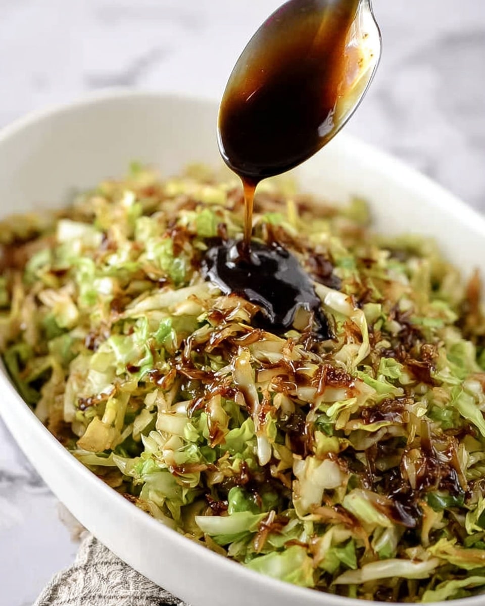 A white oval dish filled with cooked shredded green cabbage mixed with small browned bits, giving a mix of dark brown and light green colors with a slightly uneven texture. Above the dish, a spoon is dripping a thick, dark brown sauce over the cabbage. The background is a white marbled texture. photo taken with an iphone --ar 4:5 --v 7