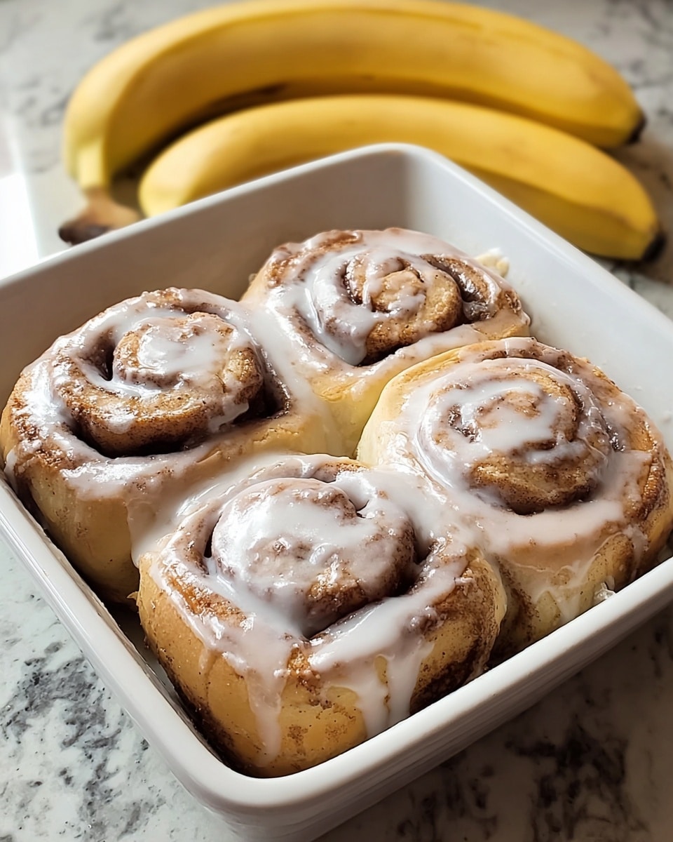 A close-up of a baking tray filled with soft cinnamon rolls arranged in two rows, each roll showing a thick swirl of brown cinnamon sugar throughout its layers, topped generously with creamy white icing that drips slightly down the sides; the texture of the rolls looks fluffy and moist, with a golden-brown crust at the base and edges. The background features a white marbled surface. Photo taken with an iphone --ar 4:5 --v 7