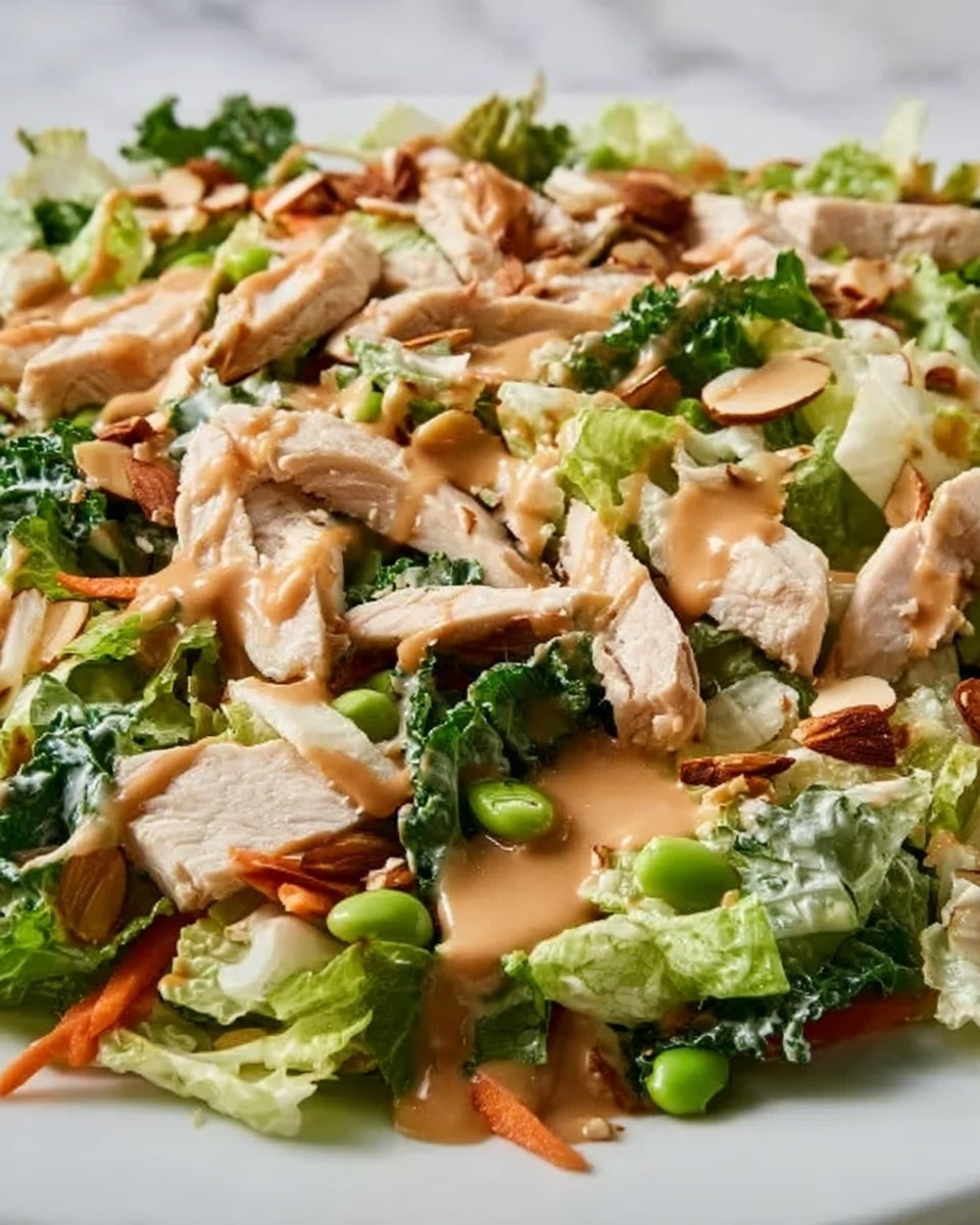 The image shows a bowl of salad with several layers and textures. The bottom layer is made of fresh green lettuce leaves, topped with thin orange carrot strips spread evenly. On top of the vegetables, there are sliced cooked chicken pieces placed in a row across the bowl. The chicken is light brown and juicy with grill marks. Scattered over the chicken and vegetables are small chopped green onions and sprinkled peanuts, adding a crunchy texture. The whole dish is finished with a glossy dark brown sauce drizzled over the chicken and salad. The bowl is white, and the background is a white marbled texture. Photo taken with an iphone --ar 4:5 --v 7