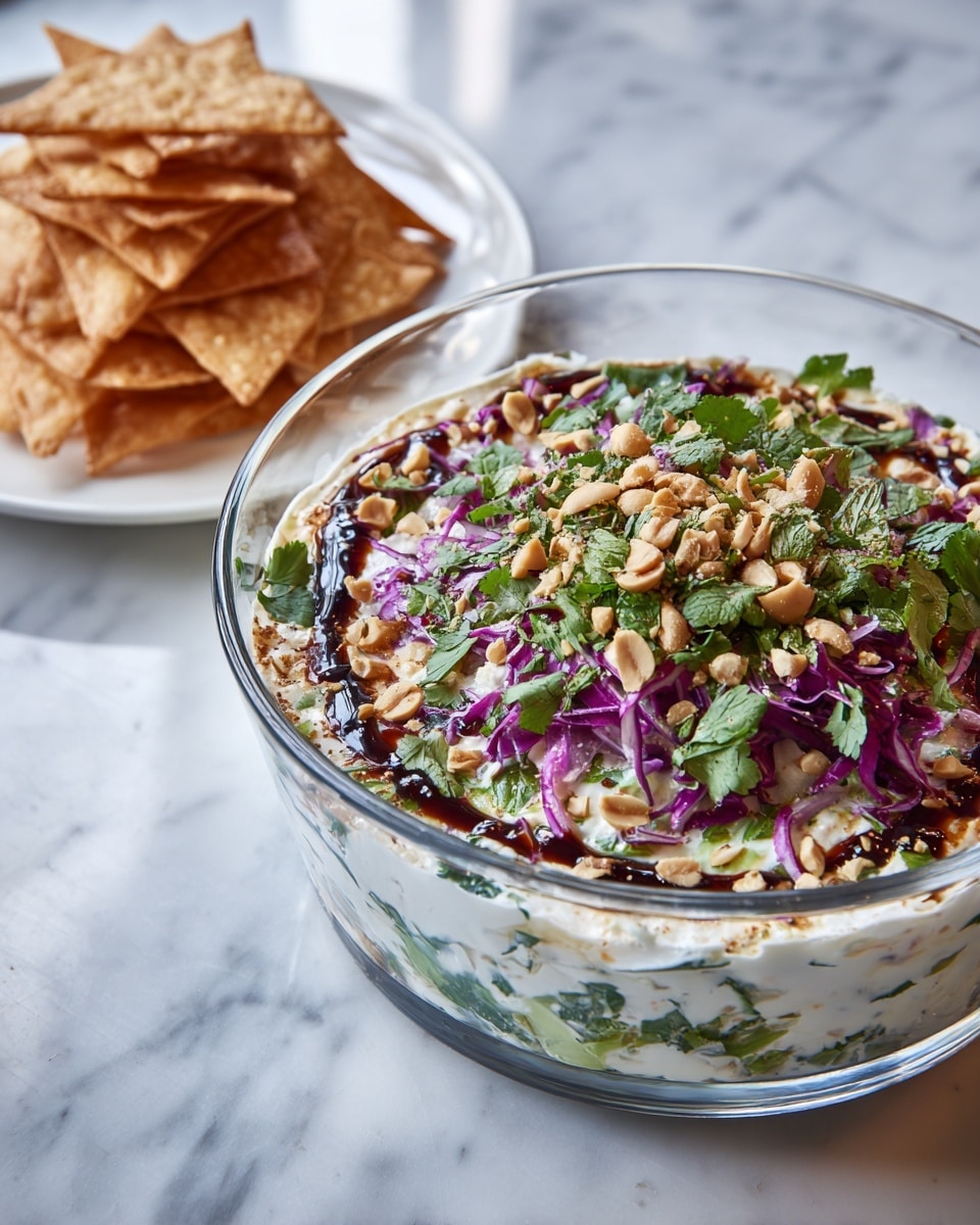 A clear glass bowl filled with a colorful salad sits on a white marbled surface. The salad has layers starting with a base of chopped white vegetables, followed by thin strips of bright purple cabbage. On top are scattered light brown chopped nuts and fresh green cilantro leaves. The salad is drizzled with a dark brown sauce, adding contrast. Next to the bowl, there is a white plate holding triangular, golden-brown crispy chips, arranged neatly. Photo taken with an iphone --ar 4:5 --v 7