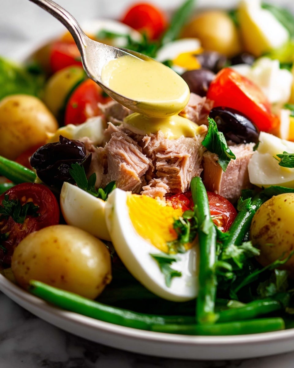 The image shows a close-up of a colorful salad in a white bowl on a white marbled surface. The salad has layers starting with green beans and leafy greens at the bottom, followed by whole small yellow potatoes and chunks of pink tuna. On top, there are quartered hard-boiled eggs with bright white and yellow colors, tomato wedges, and black olives. Fresh green parsley leaves are sprinkled throughout the salad, and a creamy yellow dressing is being poured over the top from a spoon. The textures are soft and fresh with a mix of bright and earthy tones. Photo taken with an iphone --ar 4:5 --v 7