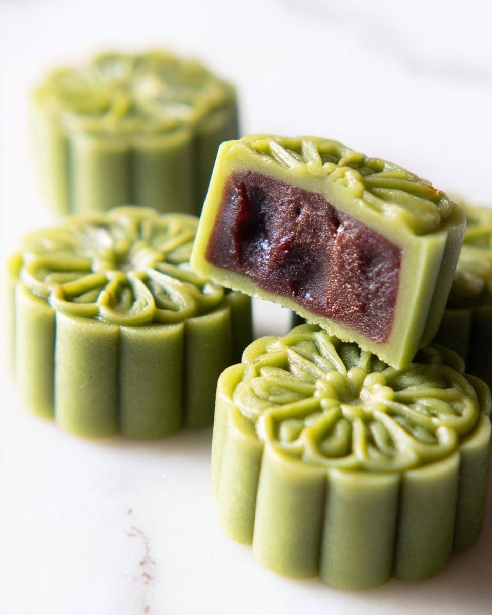 Four square green mooncakes with a detailed flower pattern on top are placed on white parchment paper over a white marbled surface. Each mooncake has a smooth texture, with subtle darker green spots hinting at the filling inside. The mooncakes are arranged loosely, showing their thick, layered edges that curve gently. The lighting is soft, highlighting the delicate shapes and the fresh green color of the mooncakes. photo taken with an iphone --ar 4:5 --v 7