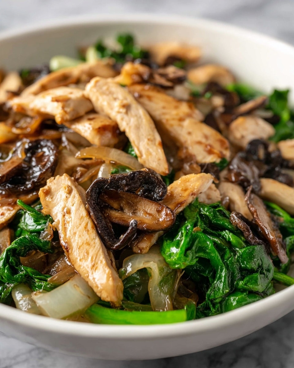 A close-up view of a dish in a white bowl showing three main layers. The top layer has light brown cooked chicken strips with some slight browning. Below and mixed with the chicken are dark brown sliced mushrooms with a slightly wrinkled texture. The bottom layer has bright green leafy vegetables and some translucent cooked onions. The whole dish looks saucy and glossy, placed on a white marbled surface. photo taken with an iphone --ar 4:5 --v 7
