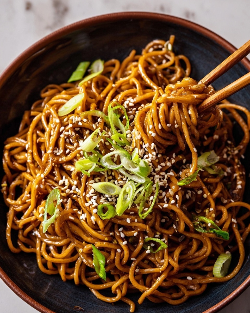 A dark bowl filled with brown cooked noodles twisted into small nests with a glossy sauce coating them. The noodles are topped with white sesame seeds scattered around and thin slices of fresh green onions placed unevenly on top. The bowl is set on a white marbled surface, and wooden chopsticks rest on the edge of the bowl, holding a small bundle of noodles lifted slightly above the rest. Photo taken with an iphone --ar 4:5 --v 7